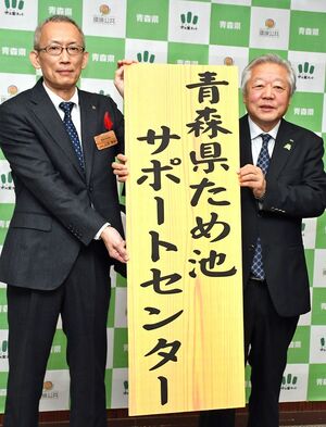 サポートセンターの看板を掲げて記念写真に納まる石澤次長（左）と野上会長