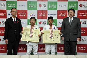 全国競技会でのメダルをかけ、賞状を手にする高谷君（中央左）と岩倉君（同右）。右端は高谷団長、左端は五十嵐副町長