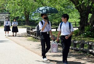 今年最高の30.7度を観測した弘前市。弘前公園では、日差しを避けながら歩く学生の姿も＝25日午後