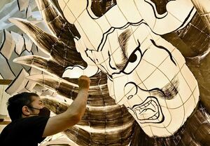 大型ねぶたの書き割り作業を進めるねぶた師の北村さん＝30日夕、青森市安方のラッセランド