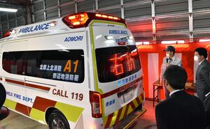 高規格救急車の説明を受ける横濱社長（右）。後部ガラスの情報板には「右折」文字が書かれている