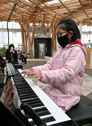 マチニワにあるストリートピアノで演奏する子ども＝昨年12月24日、八戸市