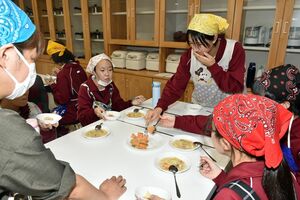 リンゴやベビーホタテ、深浦サーモンなどの地場食材を使った給食メニューを試食する家庭部の生徒たち
