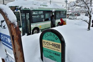 バス停が雪に埋もれ、除雪された離れた場所から乗り込む市民＝28日午後1時10分、青森市緑3丁目
