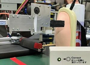 コロナワクチン自動接種ロボの試作機。二の腕の模型に注射針を刺している（弘前大学提供）