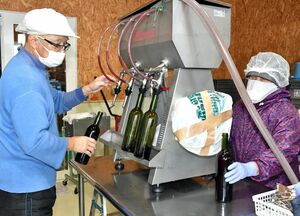 三内丸山酵母で製造したワインの瓶詰め作業に取り組む八木橋社長（左）ら