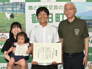 相川町長（右）から感謝状を贈られた山田さん（中）と妻園実さん（左）、娘の芽依ちゃん
