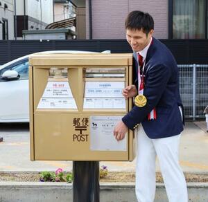 東京パラリンピック競泳男子での金メダル獲得をたたえ、出身地に設置された金色の郵便ポストに触れる木村敬一選手＝２日午前、滋賀県栗東市