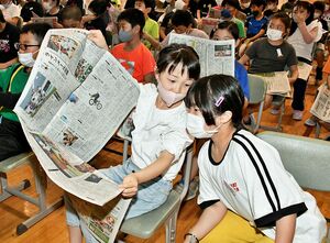 東奥日報の紙面を開いて記事の構成について話し合う児童たち