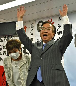 当選が決まり万歳三唱する戸田氏。左は妻厚子さん＝12日午後9時18分、六ケ所村尾駮の事務所