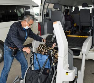 車椅子利用者の乗車を介助する桂さん（左）。30年以上勤めたタクシー会社に籍を置いたまま、出向先の通所型介護事業所で送迎業務に就く＝22日、東北町