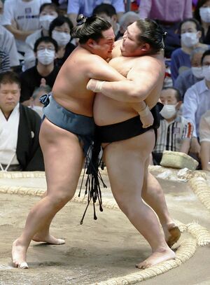錦富士（左）は千代大龍を寄り切り勝ち越し。首位の兄弟子・照ノ富士から「優勝決定戦をしよう」と励まされている（共同）