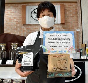 ドリップパック（右）と持ち帰り用の「かわらけつめいコーヒー」を持つ松山店主