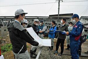 小赤川橋付近で県職員（左）から事業内容の説明を受ける国の職員ら＝26日午前、むつ市