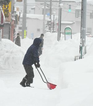 吹雪の中、雪かきに追われる市民＝31日午前10時5分ごろ、青森市篠田2丁目