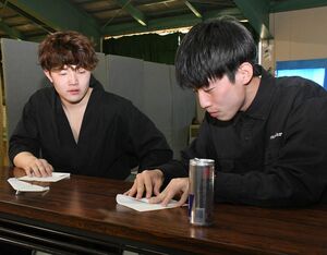 出口さん（右）から紙飛行機の折り方を学ぶ木村さん