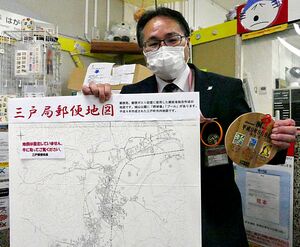 郵便地図と「平9.9.9桐タトウ」を手にする橋本局長