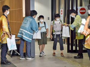 FDAの名古屋便で青森空港に到着した乗客に記念品を手渡す県職員ら