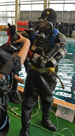 アシストスーツ試作機を腕に装着する潜水士