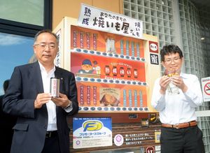 焼き芋が買える自動販売機。右が新戸部副社長、左は農福産業の担当者