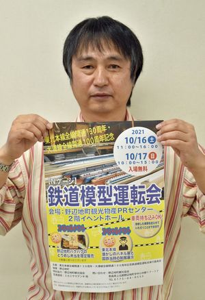 鉄道模型運転会のポスターを持ち、イベントをPRする鈴木委員長