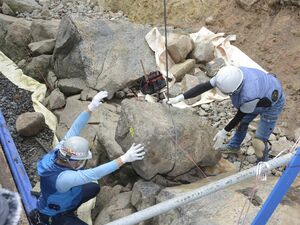 最初の石を元の位置に慎重に積み直す作業員＝23日午後1時36分、弘前公園