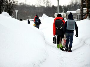 雪道を歩き登校する児童生徒ら＝17日午前7時40分ごろ、青森市内