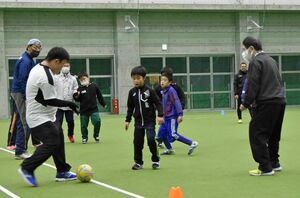 人工芝の屋内グラウンドでサッカーを楽しむ参加者＝十和田市「こまかいどーむ」
