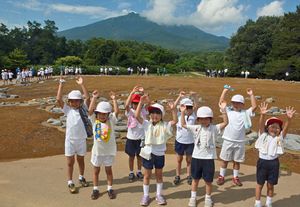 大森勝山遺跡で、世界文化遺産登録を祝う裾野小の1年生たち。後方は岩木山