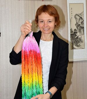 生徒たちから贈られた千羽鶴を持つマリナさん。写真に撮ってSNSでウクライナの人たちへ発信するという＝9日、八戸市の根城中学校