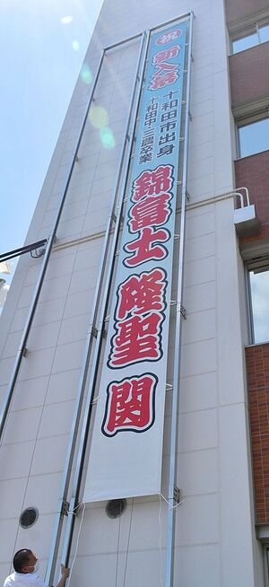 錦富士の新入幕を祝い、十和田市役所別館の外壁に取り付けられた垂れ幕＝4日午前