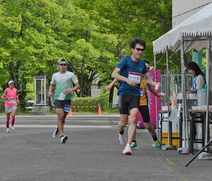 100キロマラソンで記録更新を目指し走り続ける選手ら＝26日午前8時30分ごろ、弘前市運動公園