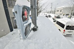 積雪が一時146センチと今季最深となった青森市。道路脇に積まれた雪で歩行者用の信号機はぎりぎり見える状態＝6日午後、同市南佃1丁目
