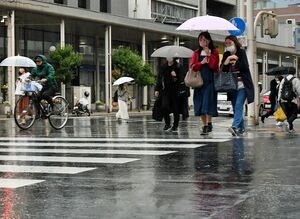 時折雨が強まる中、傘を差して歩く市民＝15日午後6時10分ごろ、青森市の新町通り