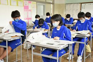 東奥日報の朝刊を開き、新聞の読み方を勉強する蟹田中の生徒ら